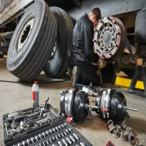 Mechanic inspecting a flatbed trailer for wear and tear during a scheduled maintenance check