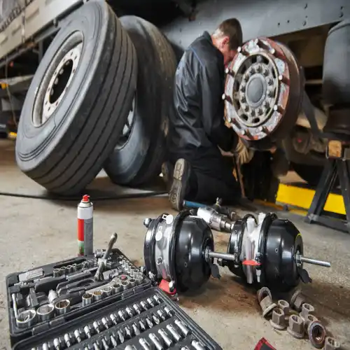 Mechanic inspecting a flatbed trailer for wear and tear during a scheduled maintenance check